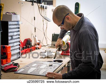 Stock Photography - Knife factory worker using blowtorch in workshop. Fotosearch