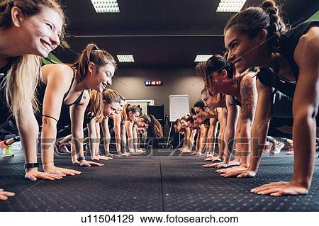 Stock Photo - Large group of women training in gym, in rows doing push ups. Fotosearch