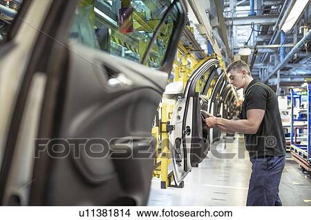 Picture - Male apprentice engineer assembling car doors in car factory. Fotosearch