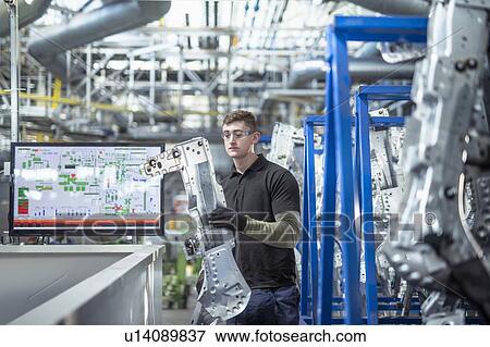 Male apprentice engineer inspecting parts in car factory View Large Photo Image Stock Photo - Male apprentice engineer inspecting parts in car factory. Fotosearch