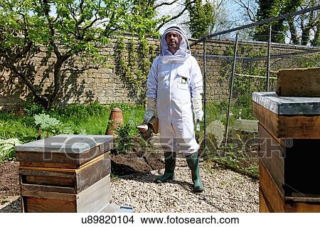 Male beekeeper carrying bee smoker in walled garden, portrait View Large Photo Image Picture - Male beekeeper carrying bee smoker in walled garden, portrait. Fotosearch