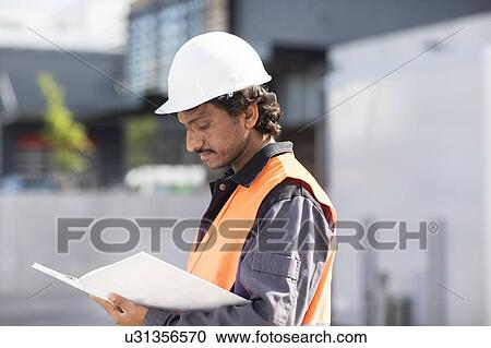 Male engineer looking at plans by industrial building View Large Photo Image Stock Image - Male engineer looking at plans by industrial building. Fotosearch