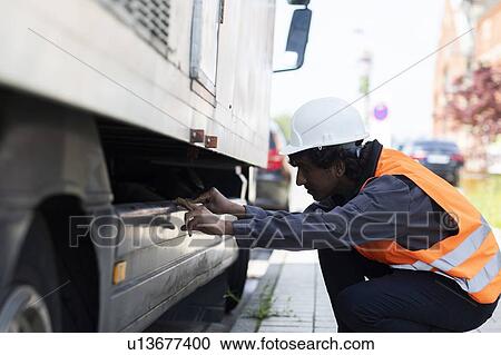 Male engineer looking beneath truck View Large Photo Image Stock Image - Male engineer looking beneath truck. Fotosearch