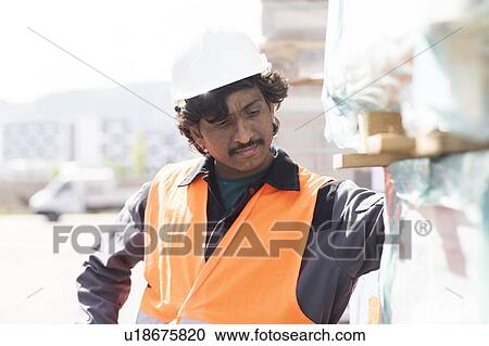 Stock Image - Male engineer on construction site inspecting construction materials. Fotosearch