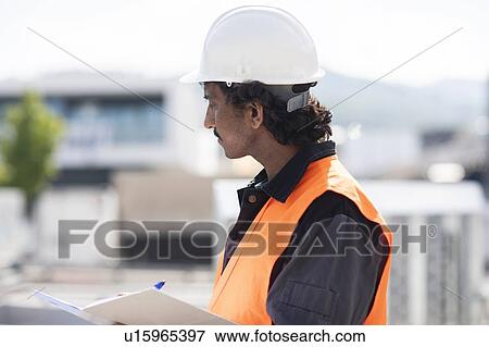 Male engineer outside industrial building writing in notebook, side view View Large Photo Image Stock Photo - Male engineer outside industrial building writing in notebook, side view. Fotosearch