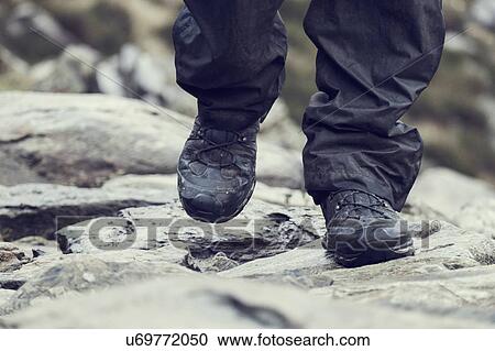 Stock Image - Male hiker hiking on rock, close up of hiking boots, Llanberis, Gwynedd, Wales. Fotosearch