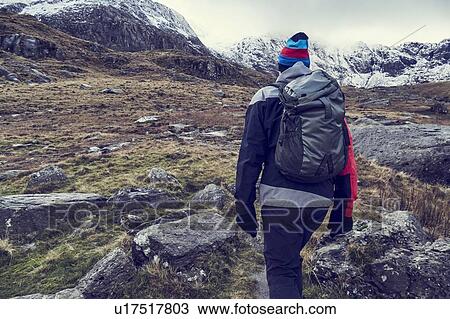 Male hiker hiking up rugged landscape with snow capped mountains, rear view, Llanberis, Gwynedd, Wales View Large Photo Image Stock Image - Male hiker hiking up rugged landscape with snow capped mountains, rear view, Llanberis, Gwynedd, Wales. Fotosearch