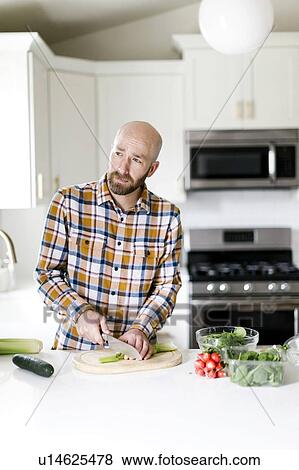 Man chopping vegetables in kitchen View Large Photo Image Stock Photo - Man chopping vegetables in kitchen. Fotosearch