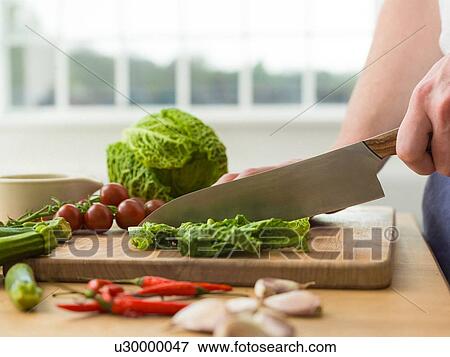 Man slicing savoy cabbage at kitchen counter, cropped View Large Photo Image Stock Photo - Man slicing savoy cabbage at kitchen counter, cropped. Fotosearch
