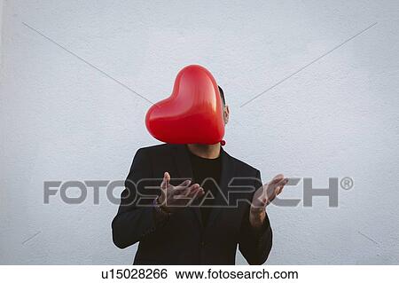Stock Photograph - Man throwing red heart shaped balloon. Fotosearch