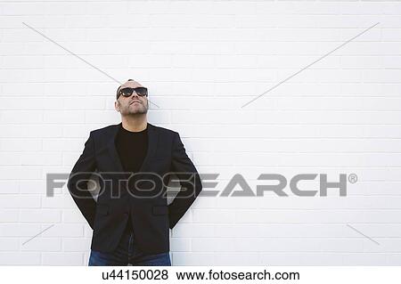 Man wearing sunglasses and blazer by white wall View Large Photo Image Stock Photo - Man wearing sunglasses and blazer by white wall. Fotosearch