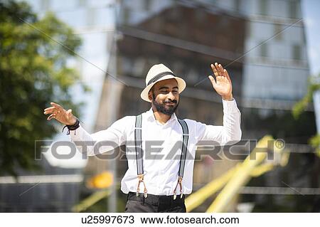 Stock Image - Man with panama hat dancing in city. Fotosearch