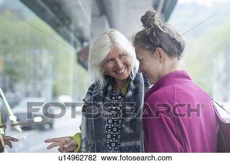 Stock Image - Mature woman and daughter window shopping in city. Fotosearch