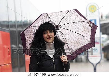 Mid adult woman carrying umbrella at city tram station View Large Photo Image Stock Photo - Mid adult woman carrying umbrella at city tram station. Fotosearch