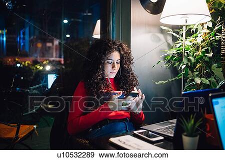 Mid adult woman looking at smartphone at cafe table View Large Photo Image Stock Photo - Mid adult woman looking at smartphone at cafe table. Fotosearch