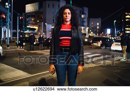 Mid adult woman with long curly hair on city street at night, portrait View Large Photo Image Picture - Mid adult woman with long curly hair on city street at night, portrait. Fotosearch