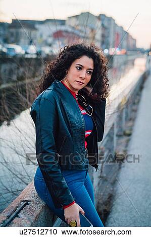 Mid adult woman with long curly hair on wall by city canal View Large Photo Image Stock Image - Mid adult woman with long curly hair on wall by city canal. Fotosearch