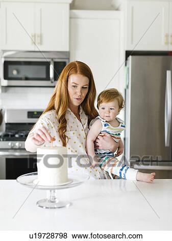 Stock Photo - Mother and baby boy by birthday cake. Fotosearch