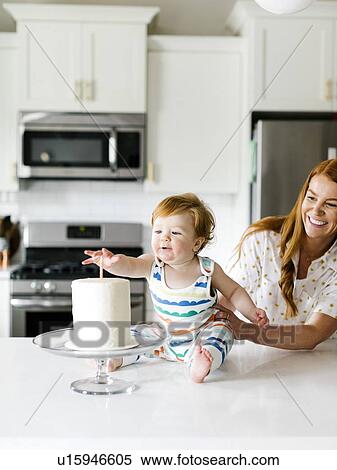Stock Photography - Mother and baby boy by birthday cake. Fotosearch