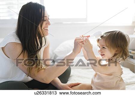 Mother and daughter on bed with hairbrush View Large Photo Image Stock Image - Mother and daughter on bed with hairbrush. Fotosearch