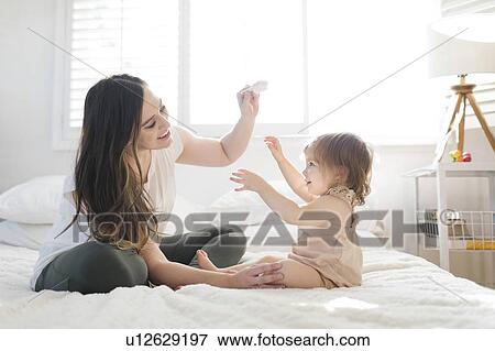 Mother and daughter on bed with hairbrush View Large Photo Image Stock Photo - Mother and daughter on bed with hairbrush. Fotosearch