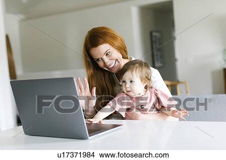 Picture - Mother and daughter using laptop to video chat. Fotosearch