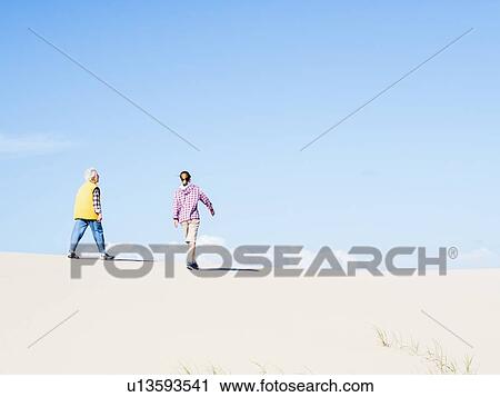 Stock Image - Mother and daughter walking on sand dune in Hawke's Nest, New South Wales, Australia. Fotosearch