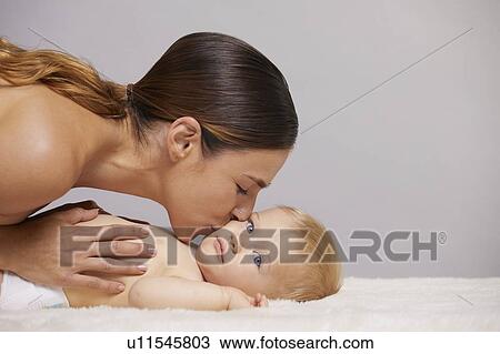 Stock Image - Mother kissing baby on cheek. Fotosearch