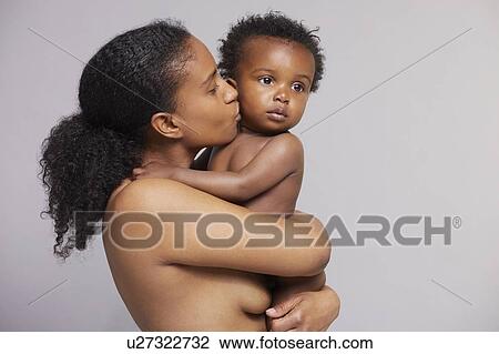 Stock Image - Mother kissing baby on cheek. Fotosearch