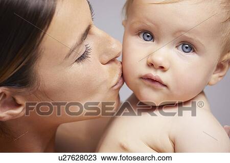 Stock Image - Mother kissing baby on cheek. Fotosearch
