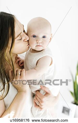 Stock Photograph - Mother kissing her baby boy's cheek. Fotosearch