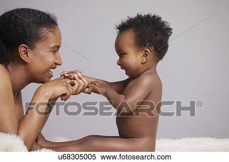 Stock Photography - Mother playing with baby sitting on furry blanket. Fotosearch