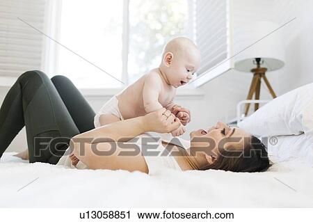 Mother playing with her son on bed View Large Photo Image Stock Image - Mother playing with her son on bed. Fotosearch