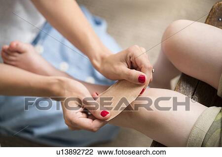 Mother putting bandage on her son's knee View Large Photo Image Stock Image - Mother putting bandage on her son's knee. Fotosearch