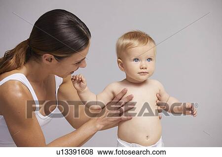 Stock Photo - Mother supporting baby on feet. Fotosearch