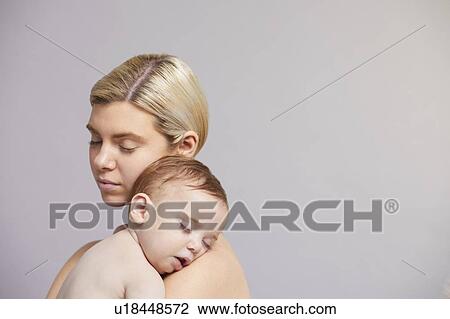 Stock Image - Mother with baby boy sleeping on shoulder. Fotosearch