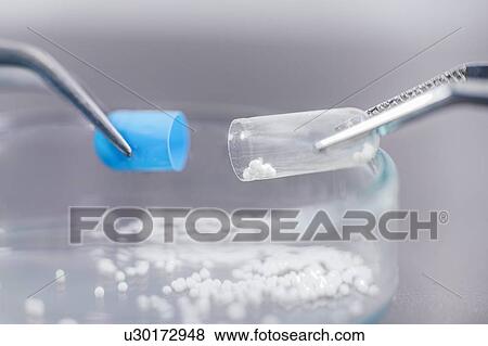 Stock Photo - Pharmaceutical worker examining a pill. Fotosearch
