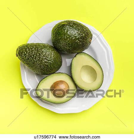Picture - Plate of avocados on green surface. Fotosearch