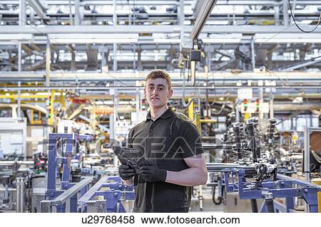 Stock Photo - Portrait of apprentice engineer with digital tablet in car factory. Fotosearch