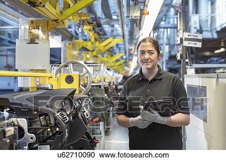 Stock Image - Portrait of female worker on dashboard assembly line in car factory. Fotosearch