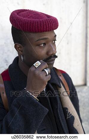 Stock Image - Portrait of stylish man with hat twirling his moustache. Fotosearch