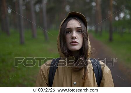 Stock Photography - Portrait of young woman wearing brown raincoat. Fotosearch