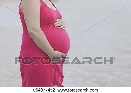 Pregnant woman wearing pink dress on beach View Large Photo Image Stock Image - Pregnant woman wearing pink dress on beach. Fotosearch