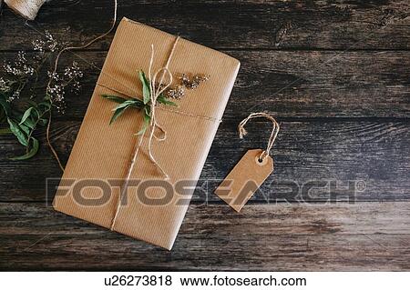 Stock Photo - Present wrapped in brown paper and string with label and flowers. Fotosearch