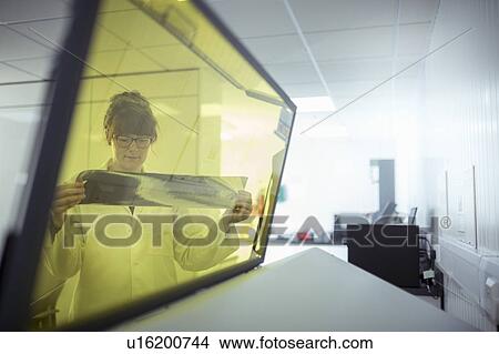 Picture - Print scientist examining sample laser etched foil in print factory. Fotosearch