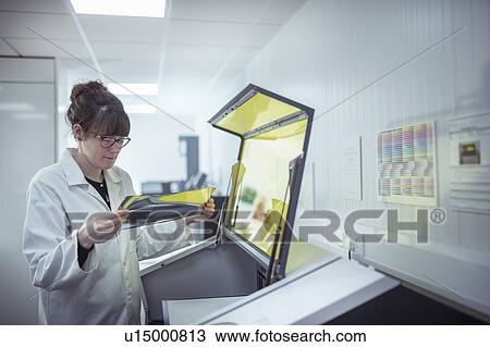 Stock Image - Print scientist examining sample laser etched foil in print factory. Fotosearch
