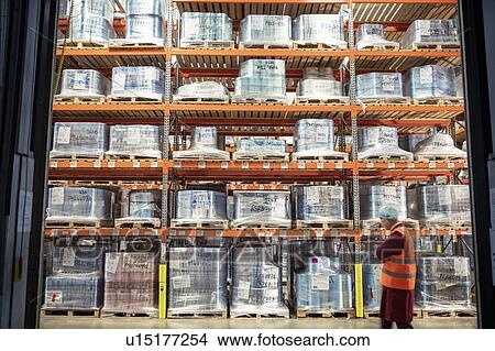 Picture - Printed food packaging in storage in print factory and worker. Fotosearch