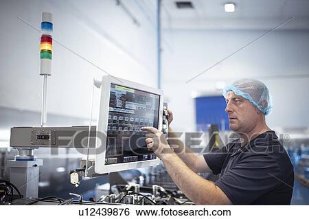 Stock Photograph - Printer using control screen of food packaging printing machine in print factory. Fotosearch