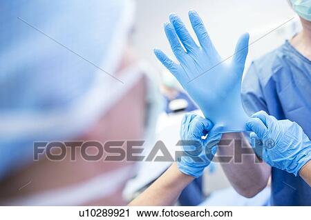 Stock Image - Putting glove on surgeon. Fotosearch