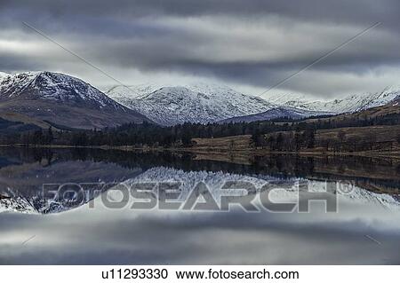 Stock Image - Reflection of snow capped mountains in lake, Scottish Borders, United Kingdom. Fotosearch